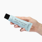 Hand holding a tube of Biome Boost Cream daily moisturizer with probiotics and prebiotics to sooth the red inflamed skin.