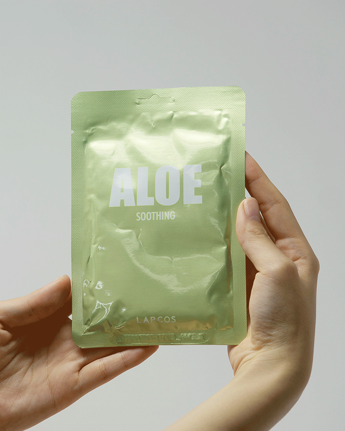 removing the single use soothing aloe vera face mask from its packaging